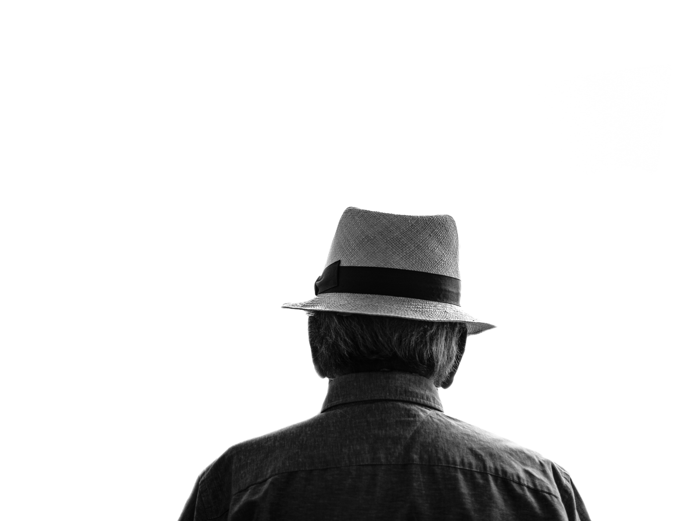 An old man wearing a hat photographed from behind