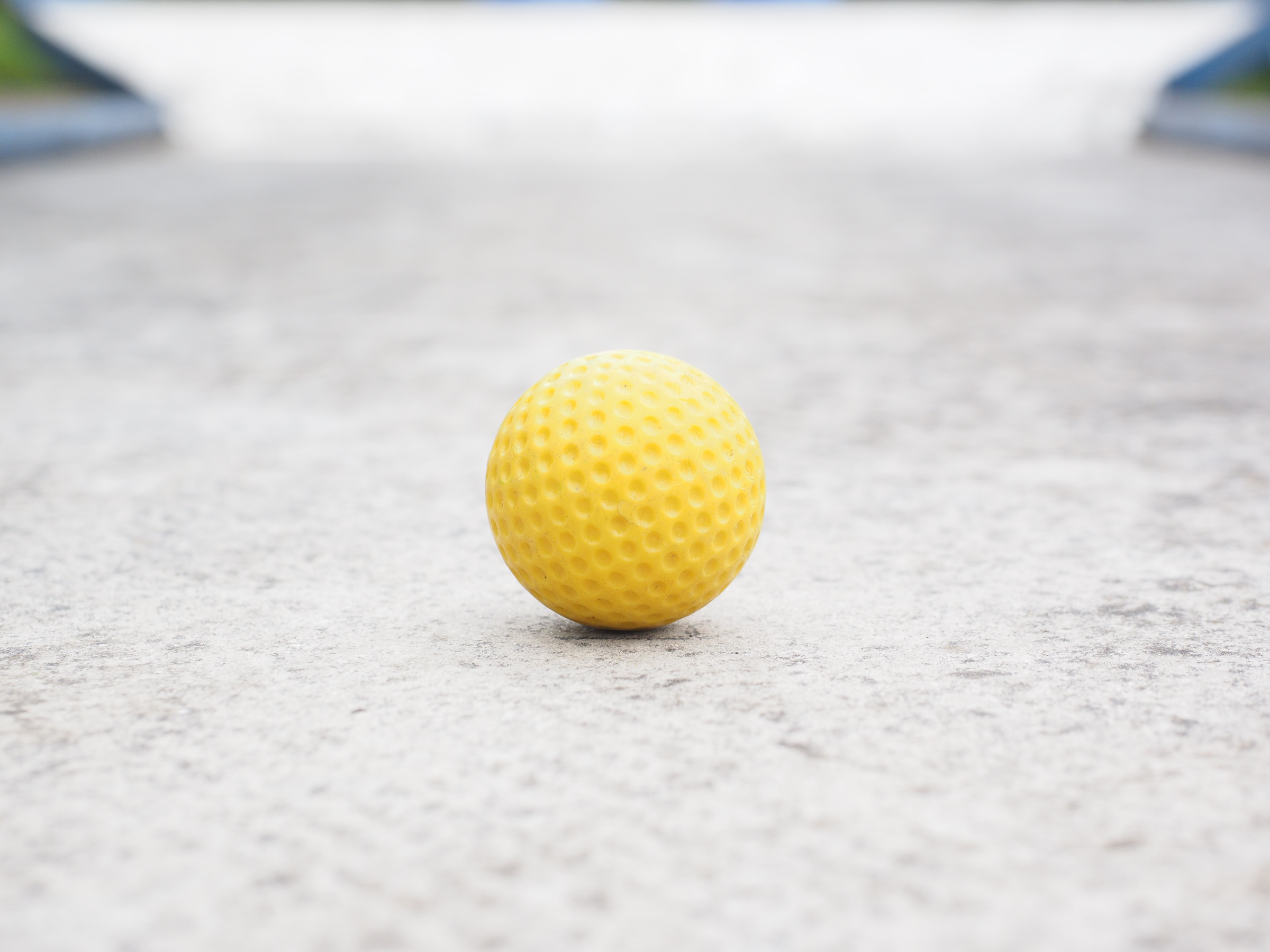 A yellow golf ball on a minigolf lane