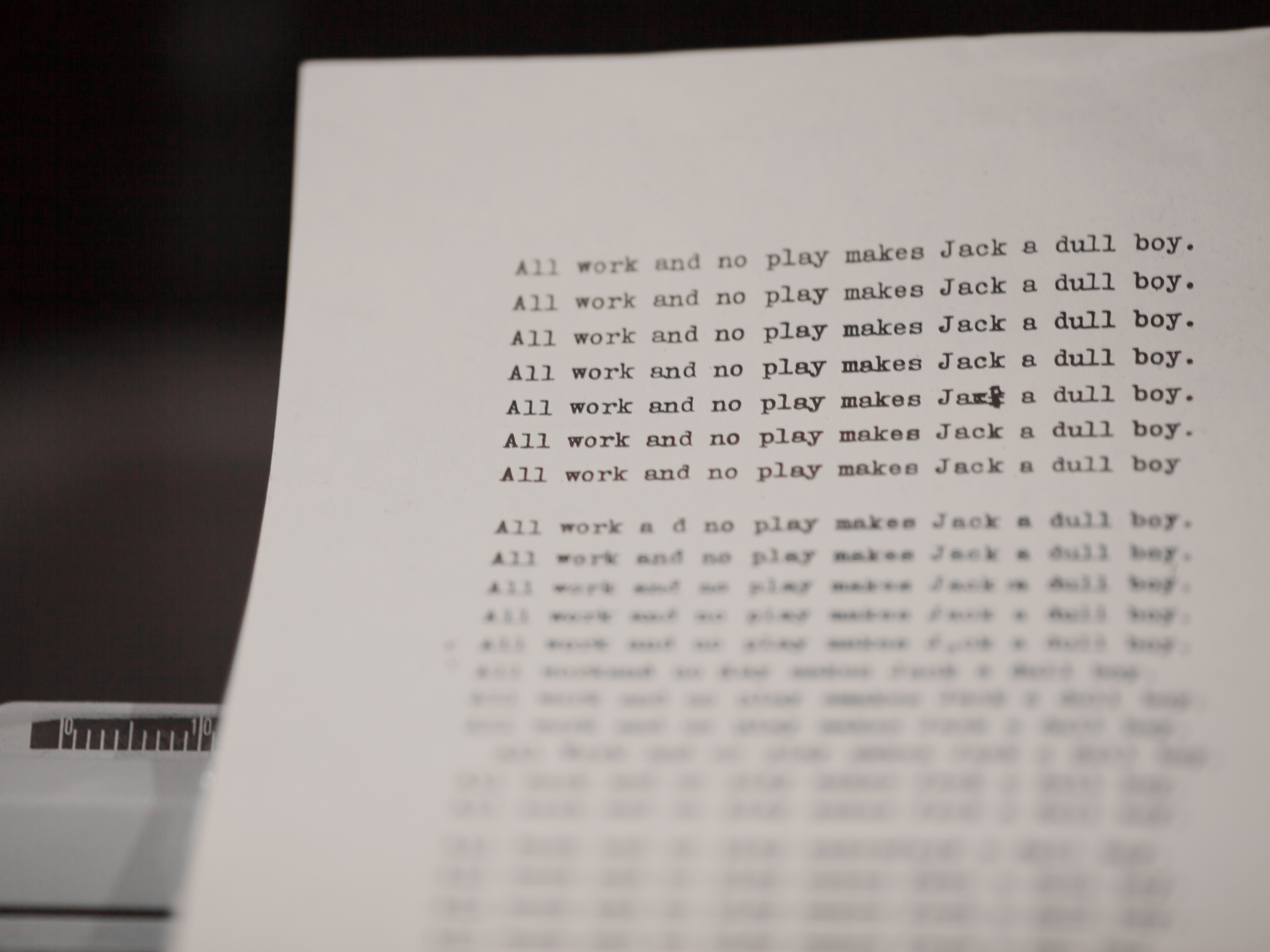 A page in a typewriter with the words "All work and no play makes Jack a dull boy" from the movie The Shining.