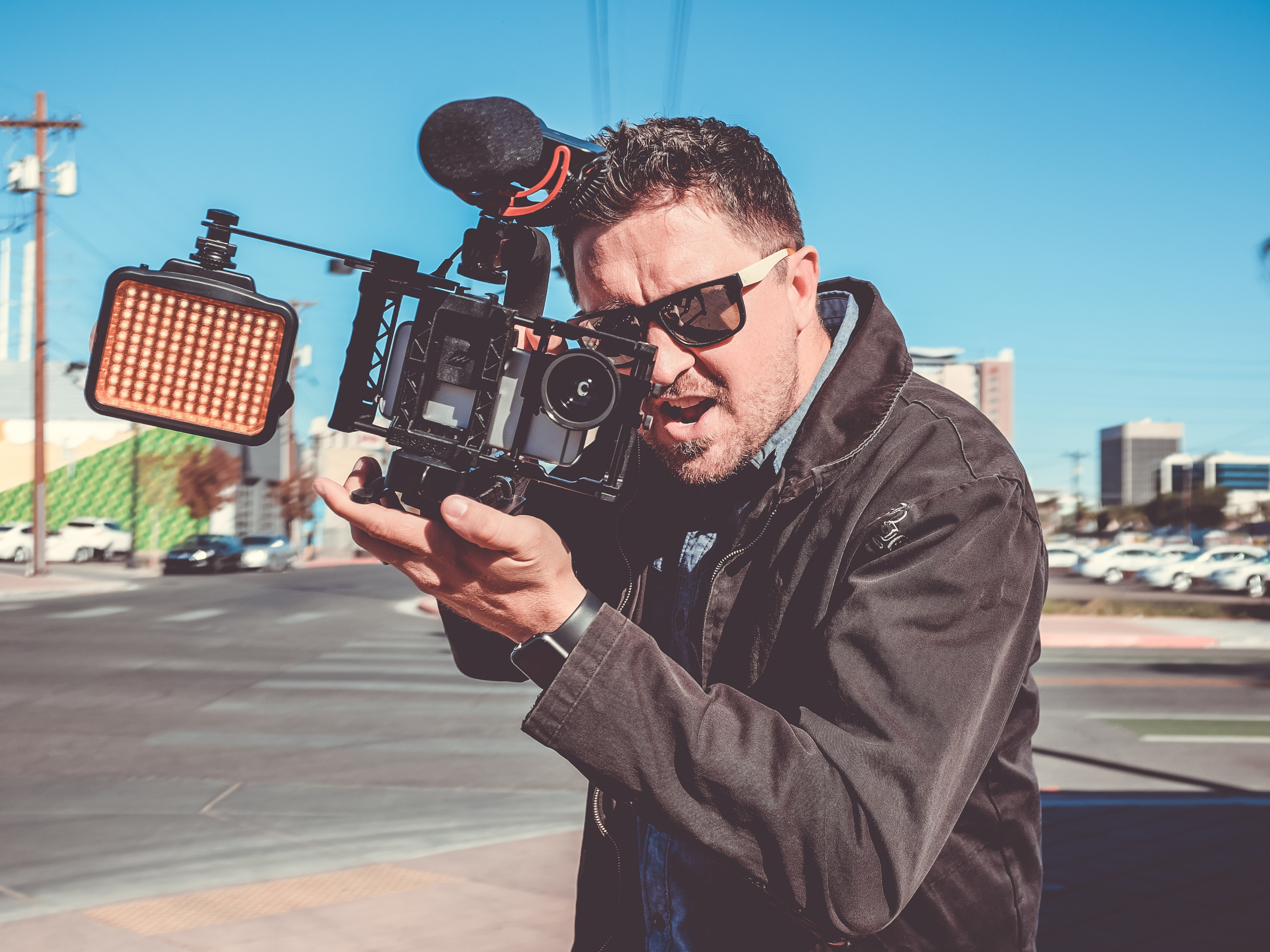 A man with a camera shooting video on the street.